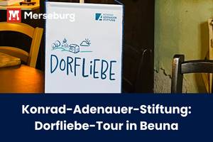 Beitragsbild Dorfliebe-Tour in Beuna Das Plakat der Dorfliebe-Tour hinter einem kleinen, runden Esstisch